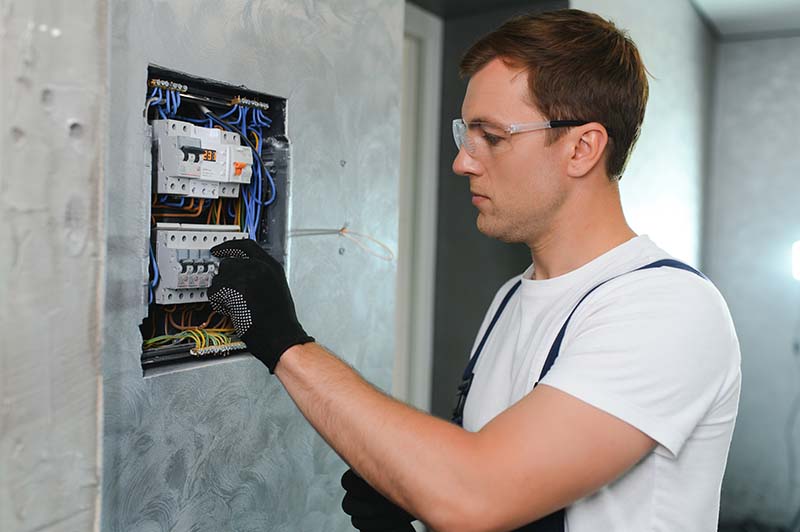 The electrician is repairing an electrical panel in a residential property.